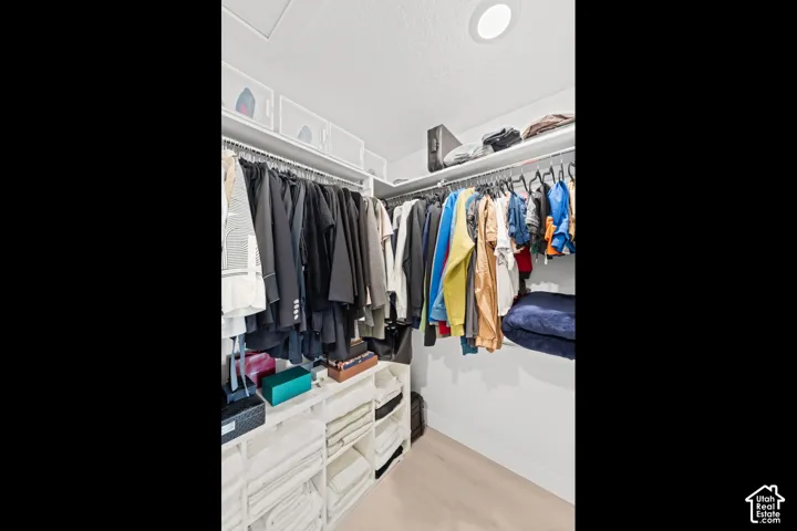 Custom closet system with multiple hanging rods, integrated shelving units, and light wood-finish flooring