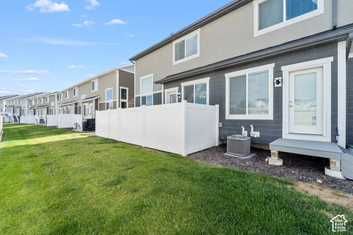 Expansive green space featuring a white privacy fence, an exterior door with glass insert, and a compact outdoor living area