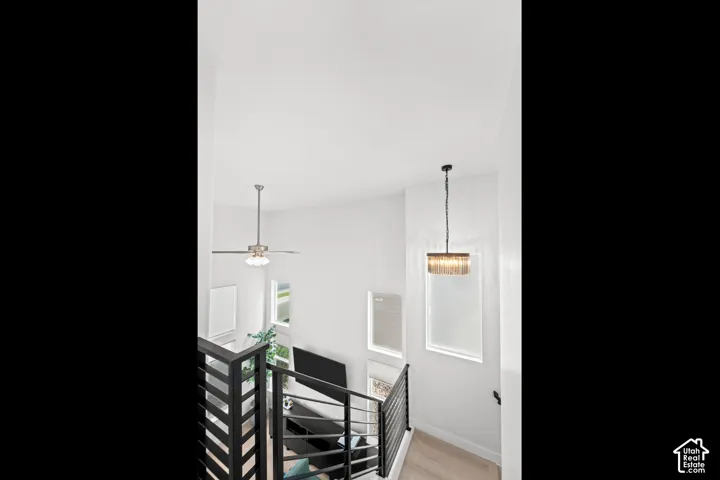 Loft space with a linear chandelier, ceiling fan, and black metal stair railing