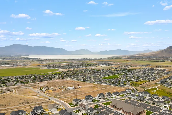 Expansive aerial perspective showcasing a residential development, a substantial body of water, and distant mountain ranges