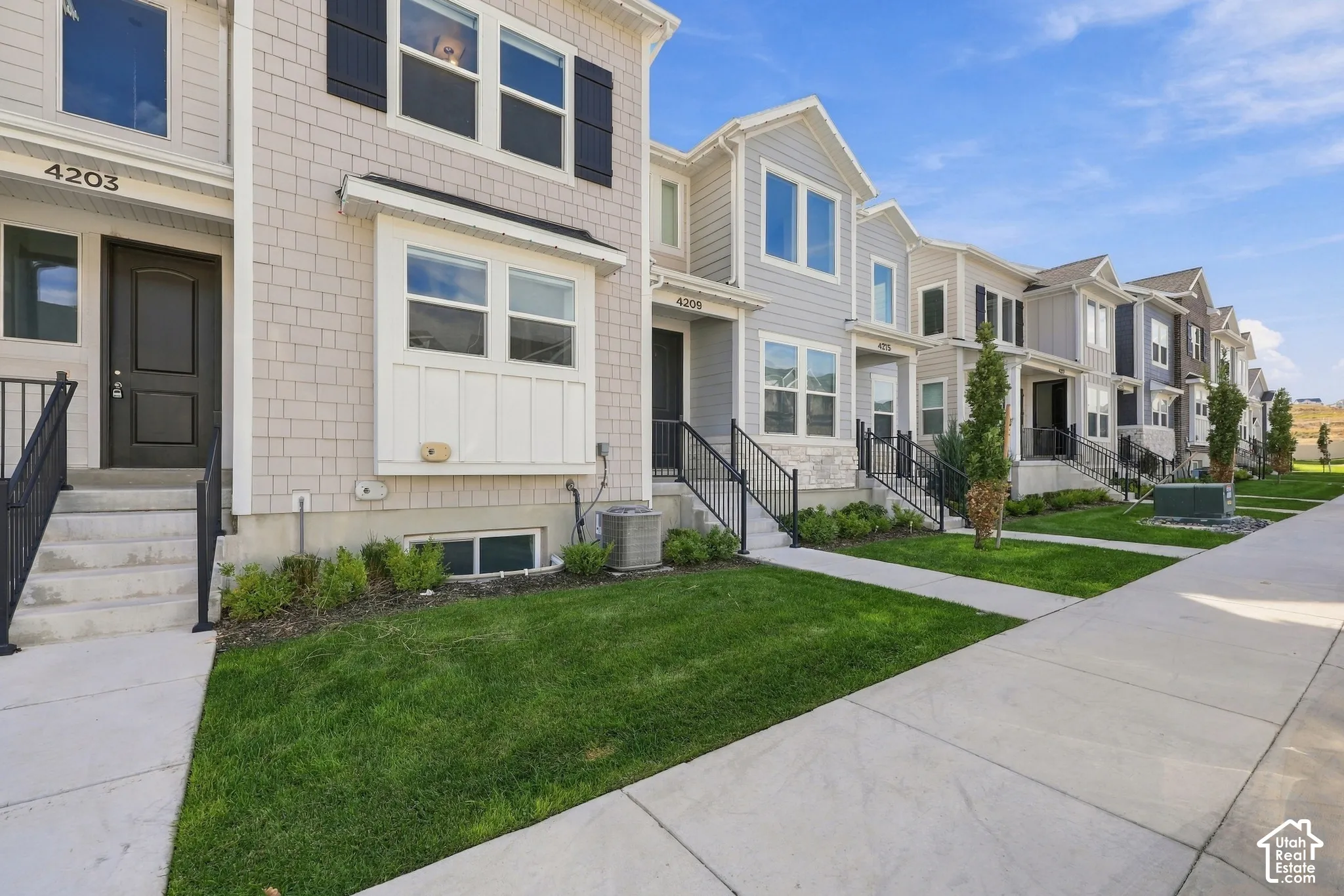 Multi-story townhouse with shingle siding and dark contrasting shutters