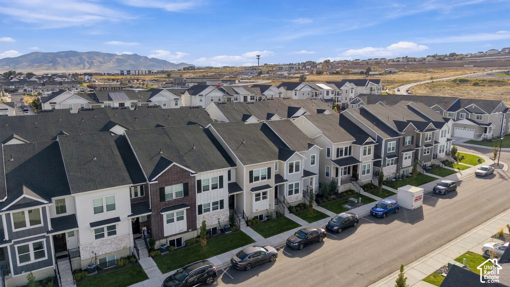 Row of contemporary townhomes featuring varied exterior finishes, uniform dark shingle roofs, and individual front entrances