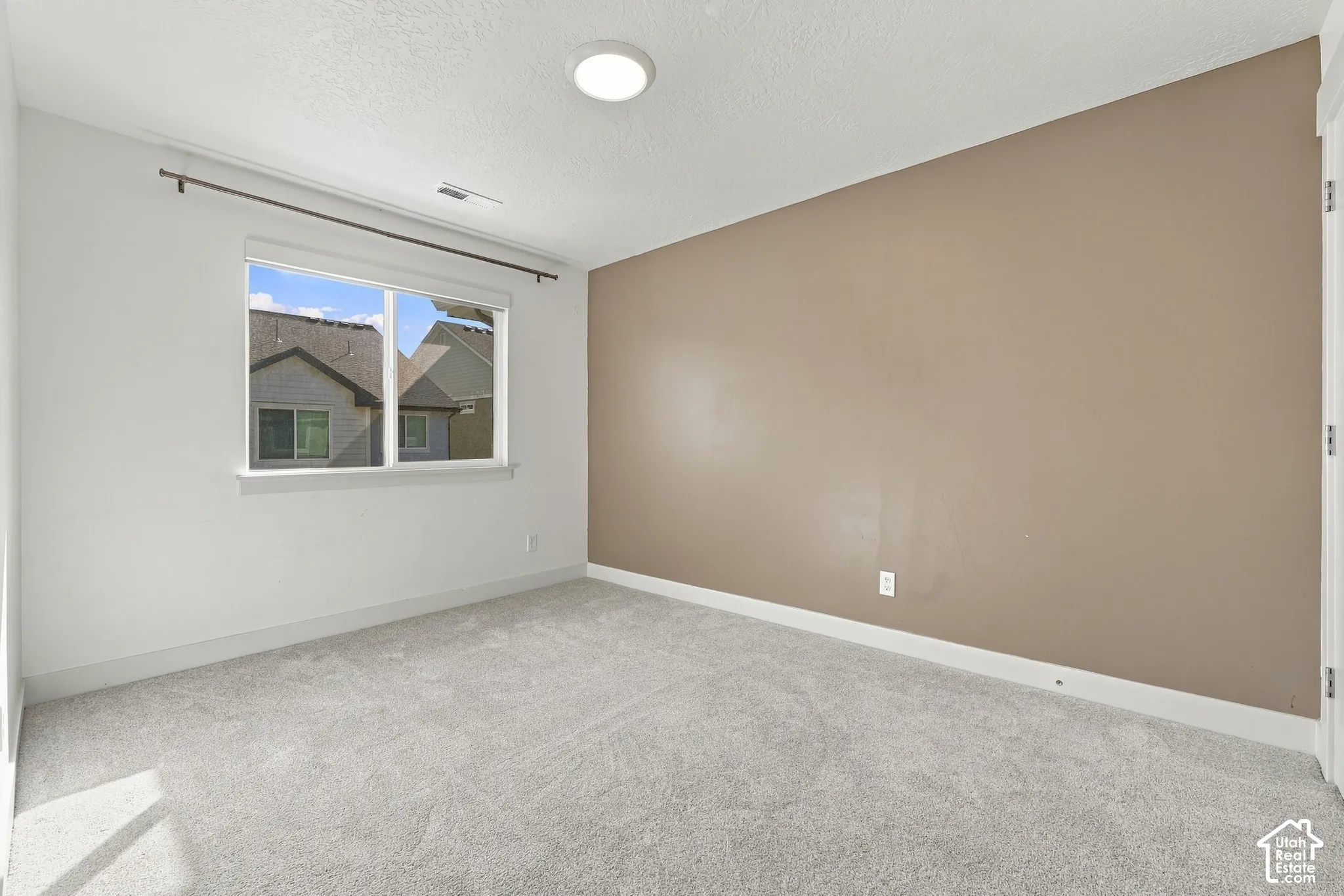 Recessed ceiling light fixture, neutral carpet flooring, white walls, and a feature wall