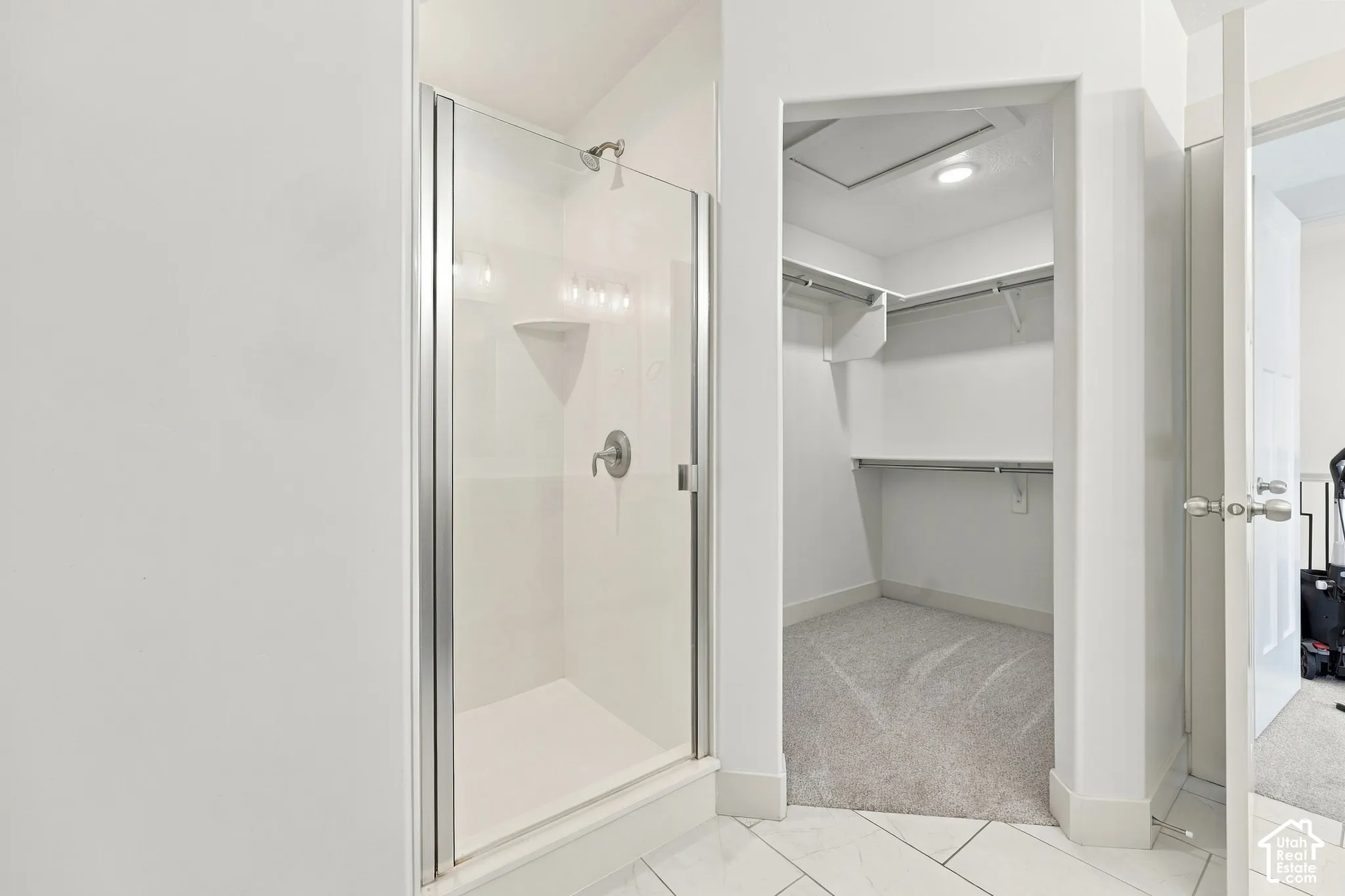 Walk-in shower with clear glass enclosure and shelving
