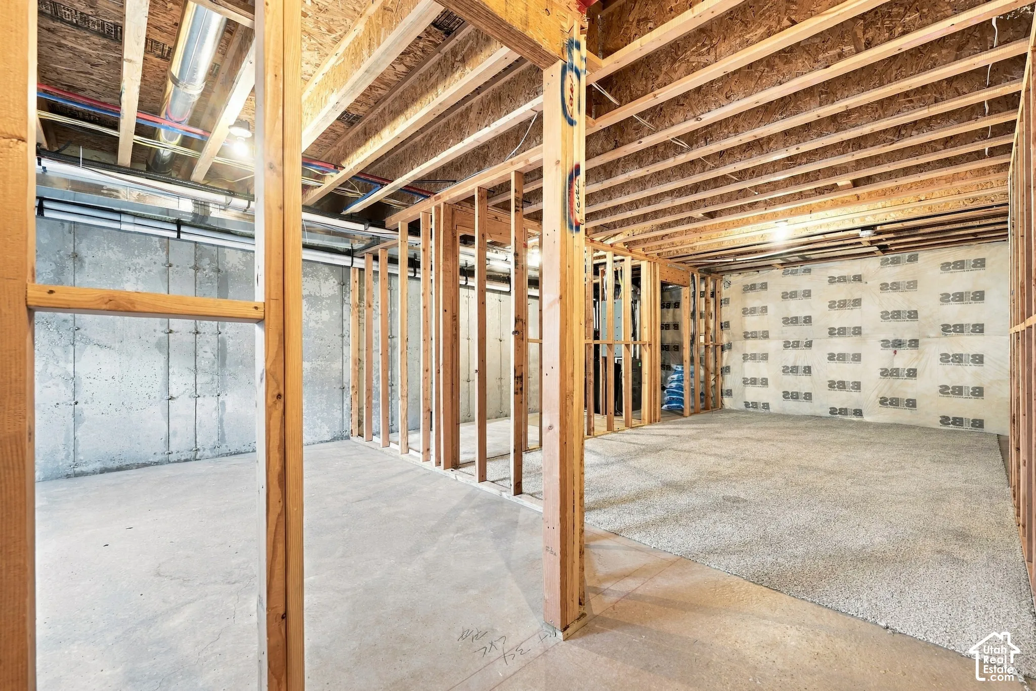 Unfinished basement featuring concrete walls and flooring, wood framing, and exposed ceiling joists