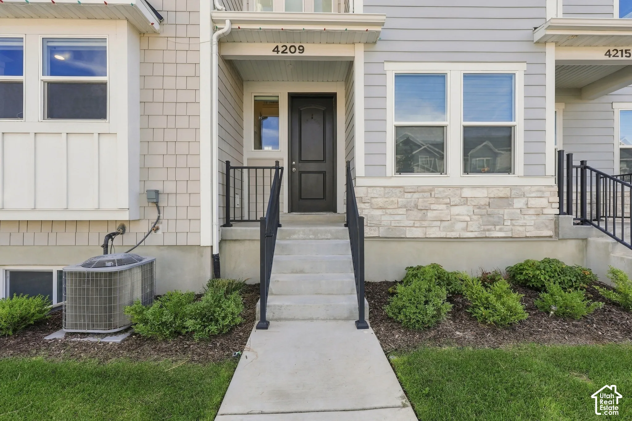 Light gray siding exterior with stone accents and a dark entry door