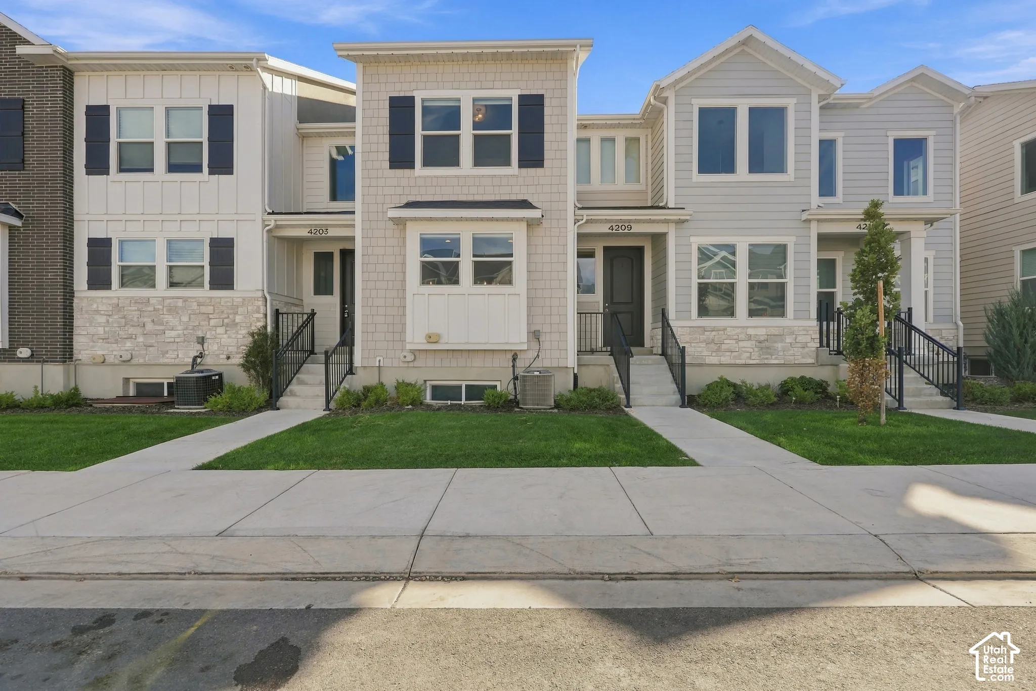 Contemporary townhomes featuring mixed-material facades with vertical siding, horizontal siding, and stone accents