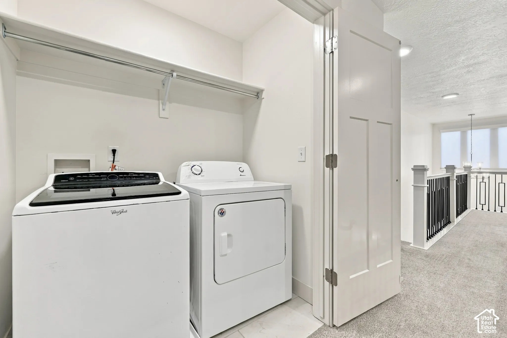Laundry space featuring a shelf with a hanging rod, white walls, and light-colored flooring