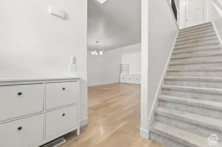 Wood-finish flooring, carpeted staircase, recessed lighting, and a modern chandelier