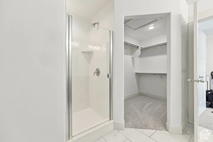 Walk-in shower with clear glass enclosure and shelving