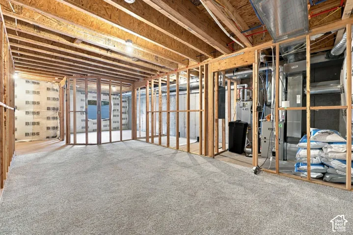 Unfinished lower level featuring wood framing, exposed ceiling joists, and carpet flooring