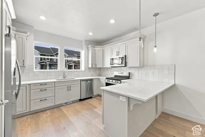 Contemporary kitchen featuring white cabinetry, stainless steel appliances, light-toned wood-finish flooring, a white subway tile backsplash, and recessed lighting