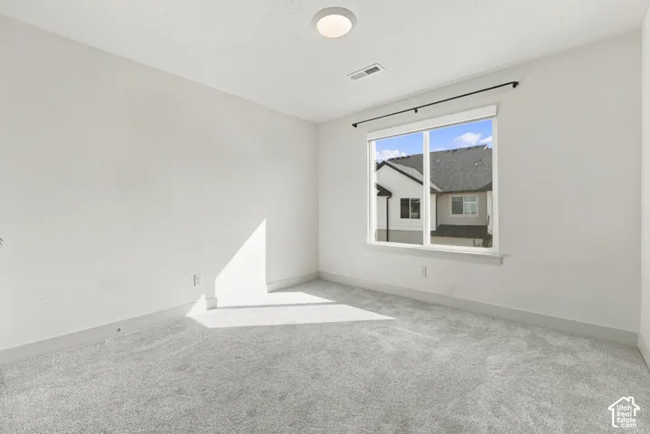 Recessed lighting, large window with black curtain rod, light gray carpeting, white walls, and white trim
