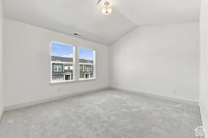 Vaulted ceiling with an attached light fixture, two windows with white trim, and light gray wall-to-wall carpeting