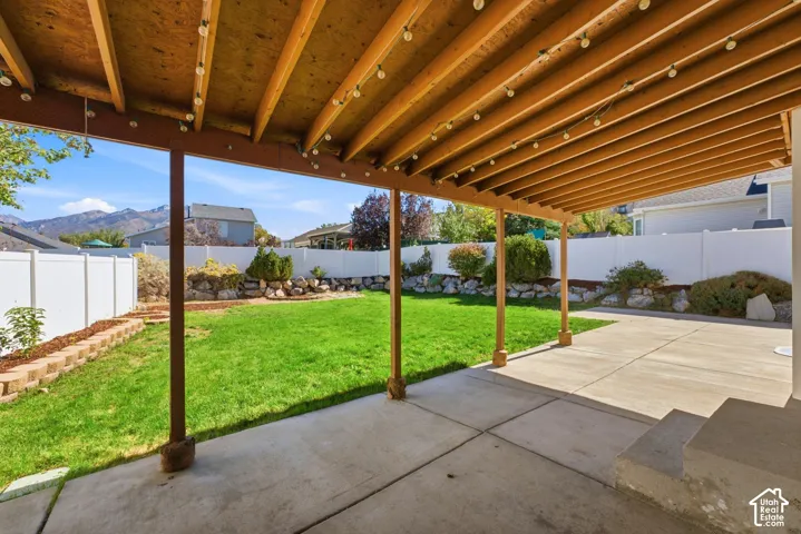 Covered patio with concrete surface, extending to a spacious yard.