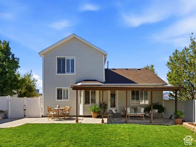 Expansive backyard featuring a green lawn, concrete patio, and a covered pergola