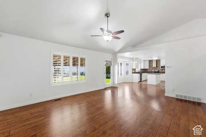 Vaulted ceiling with a ceiling fan, wood-finish flooring, and white window shutters
