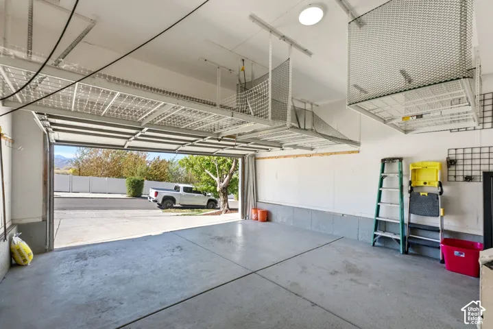 Spacious garage featuring a concrete floor, overhead storage racks, and an overhead light fixture