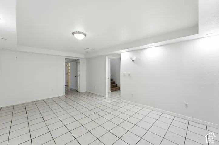 Expansive room with white tile flooring, white walls, and recessed lighting