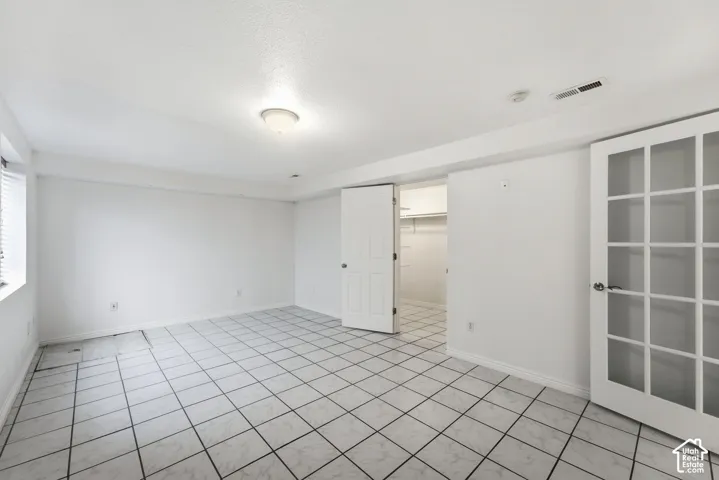 White square tile flooring, French doors, window with blinds, and recessed closet with shelving