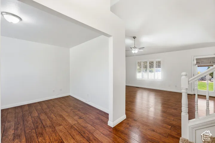 Wood-finish flooring throughout, white walls, and a white interior staircase with wood balusters