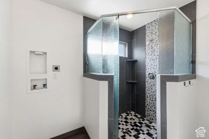 Walk-in shower featuring textured glass panels, dark tile walls, and a mosaic tile accent