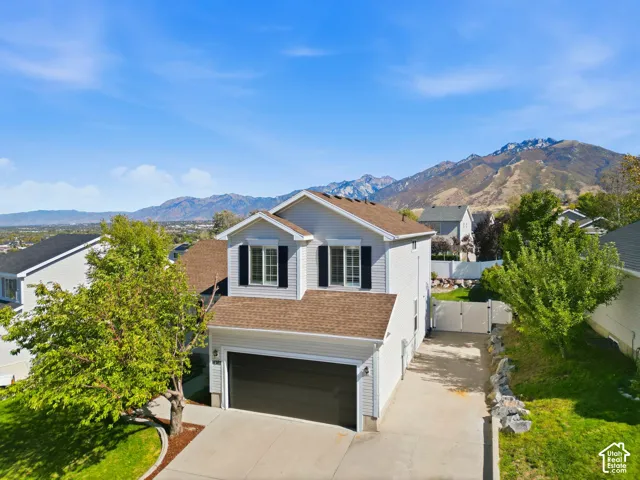 Two-story residence with a two-car garage, mountain backdrop, and a gated side yard