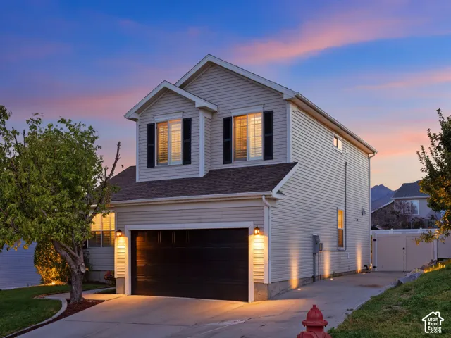Two-story exterior with light-colored siding, black garage door, and accent lighting