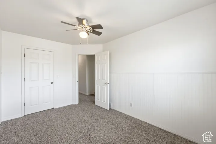 Neutral-toned carpeting, white six-panel interior doors, and a ceiling fan with integrated lighting