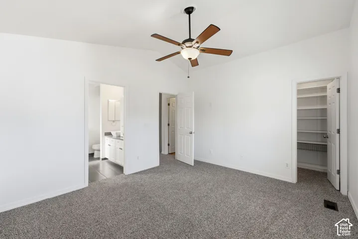 Vaulted ceiling with a ceiling fan, plush carpet flooring, white painted walls, and built-in closet shelving