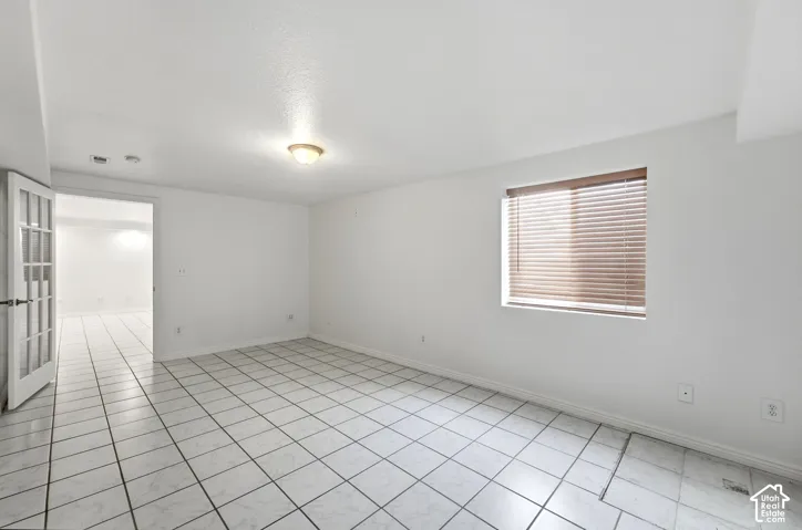 White tile flooring, single window with blinds, recessed lighting, ceiling-mounted light fixture, French doors