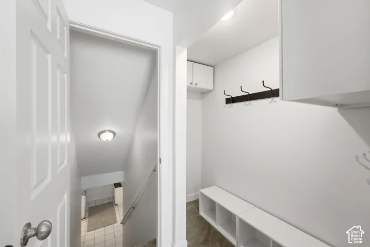 Built-in wall cabinetry, recessed lighting, wall-mounted coat rack, built-in open-shelf storage bench, and a paneled interior door