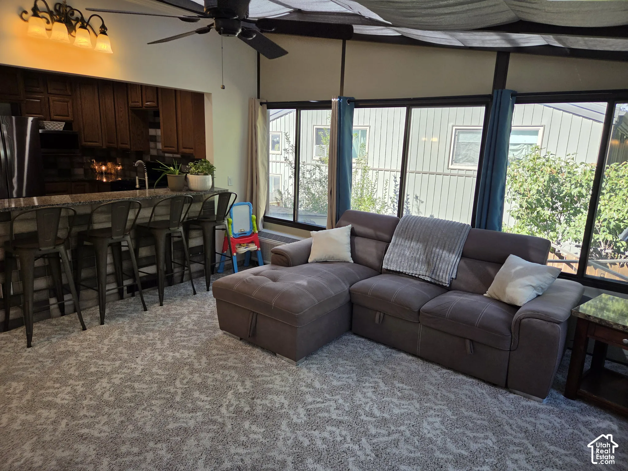 Open-concept living area with a vaulted ceiling, ceiling fan, and large windows