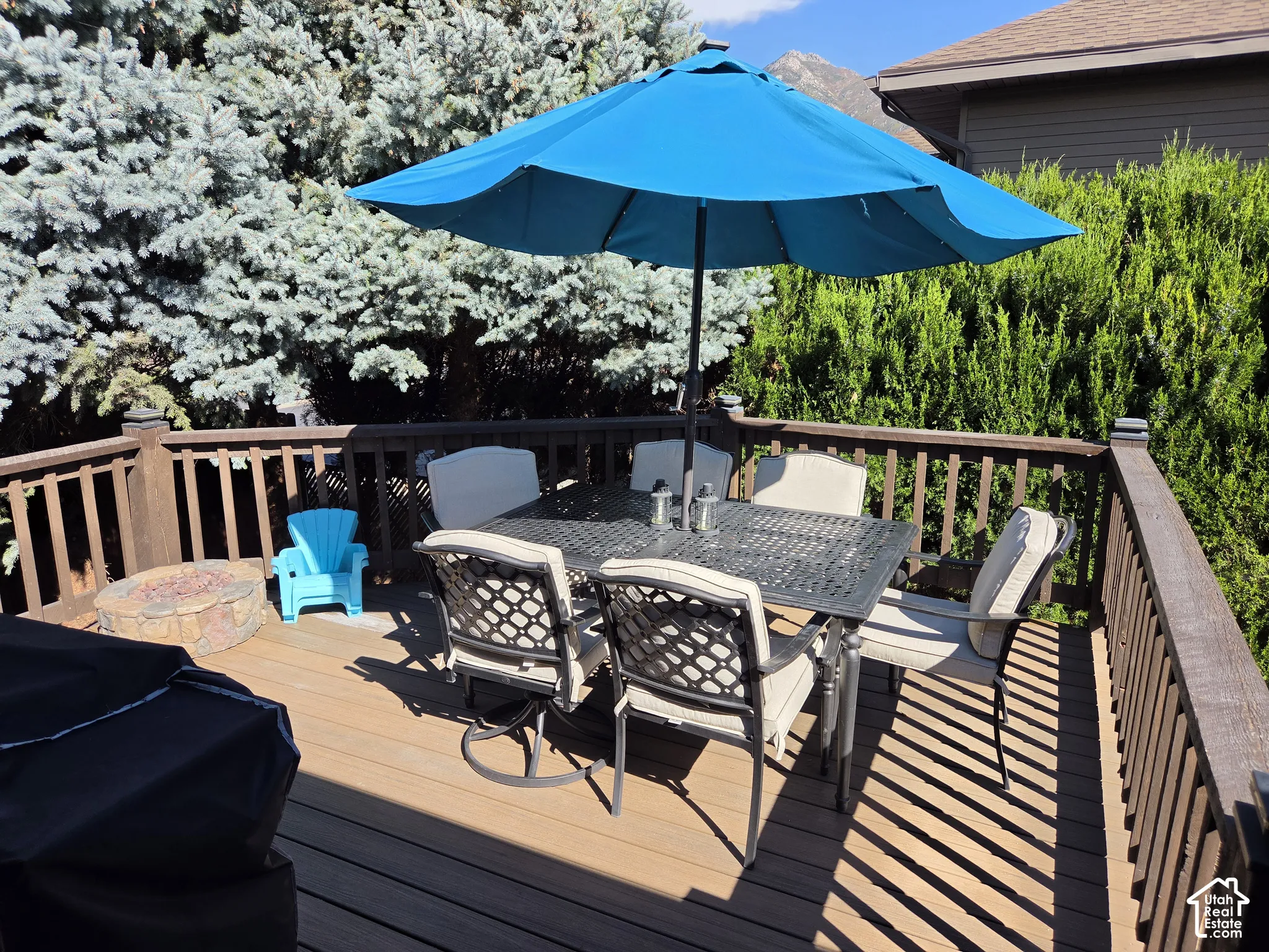Expansive outdoor deck featuring wood-finish flooring and a stone fire pit