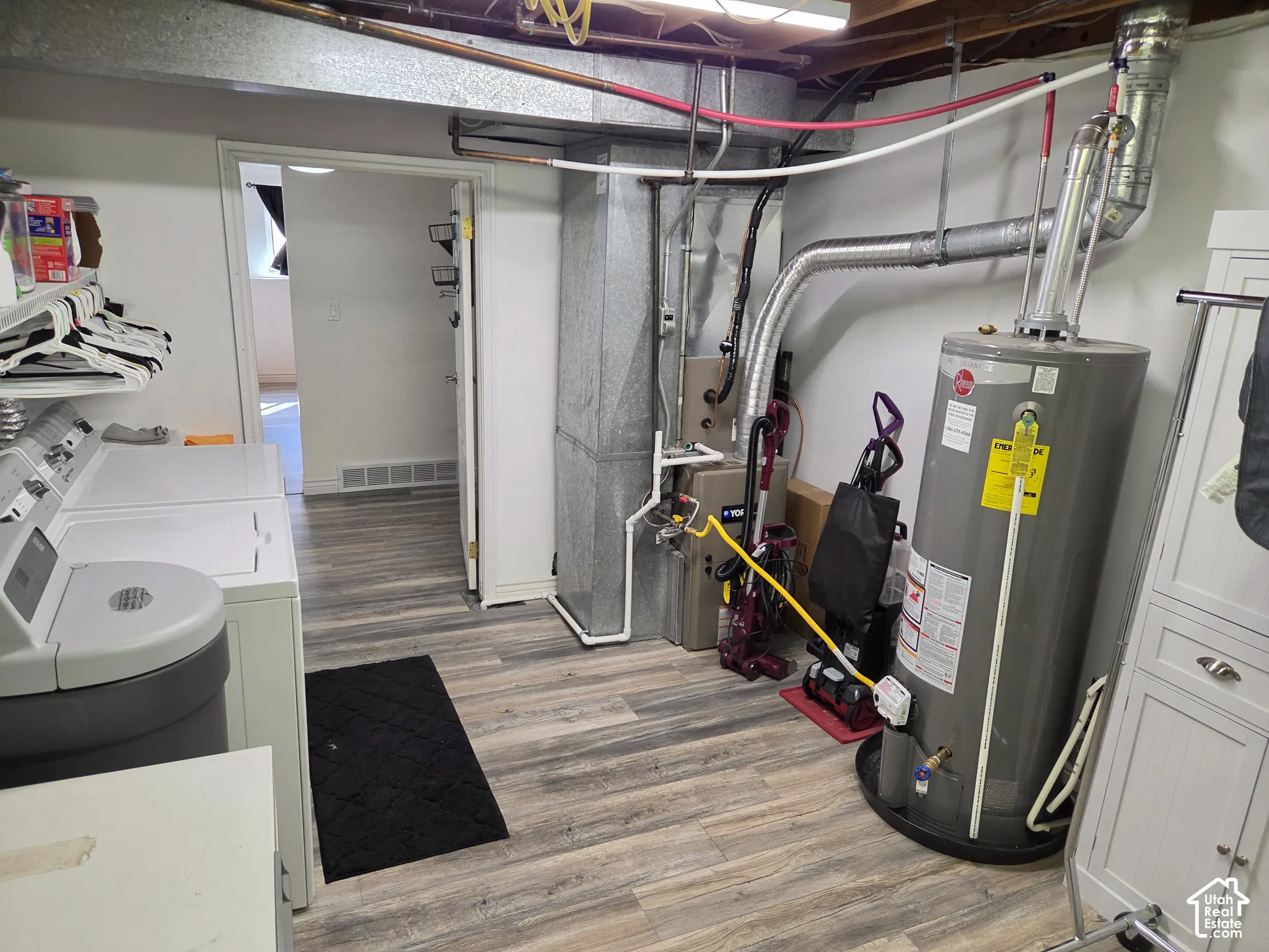 Wood-finish flooring with white baseboards, a white door frame, and a hot water heater