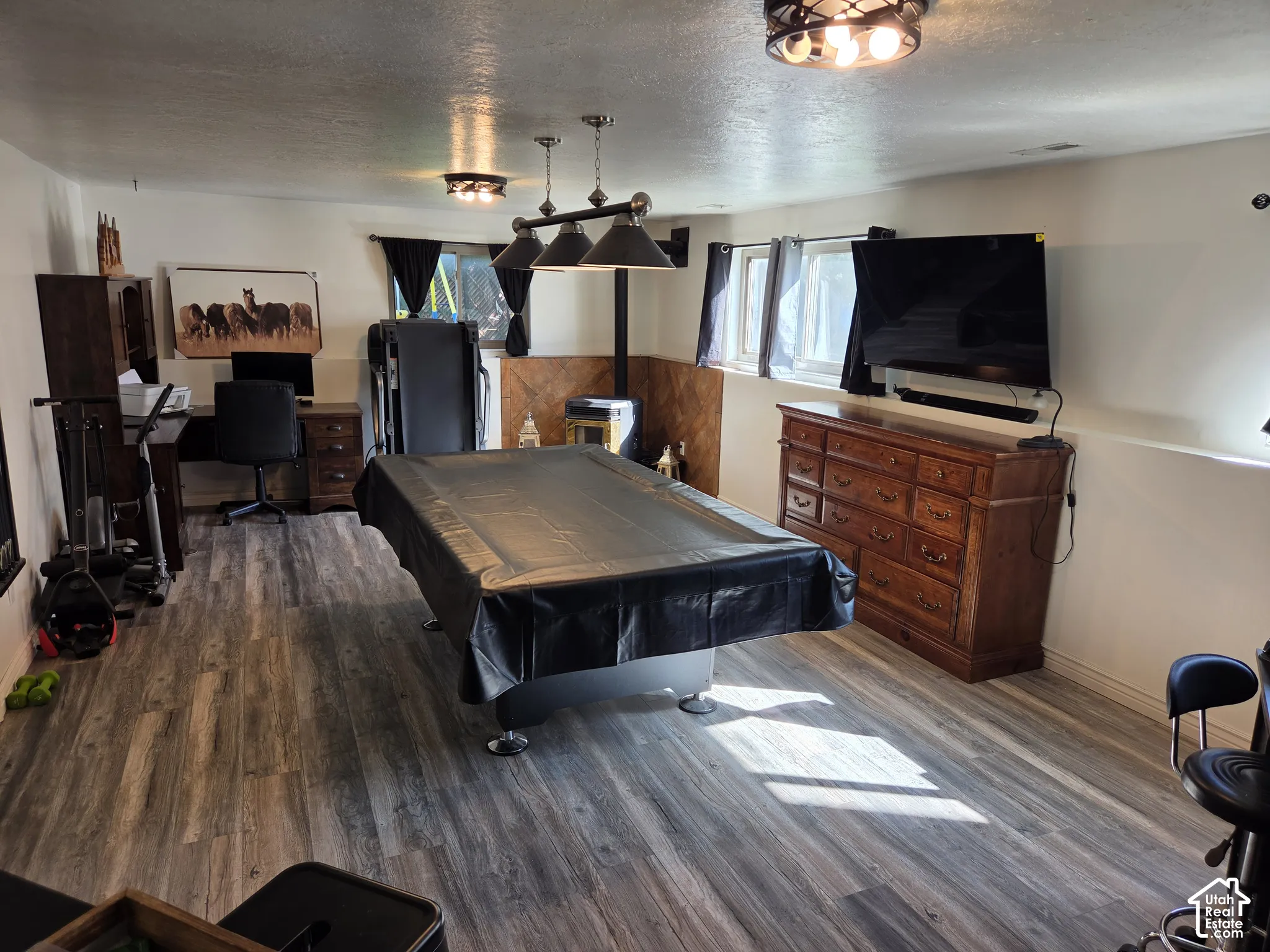 Wood-finish flooring throughout, complemented by a suspended lighting fixture and recessed windows