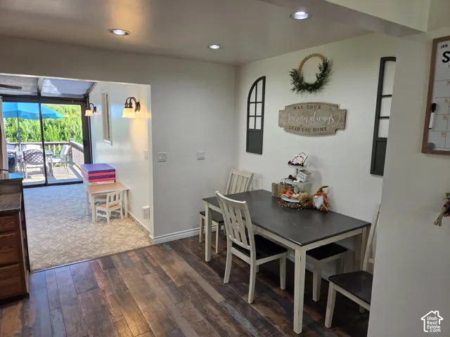 Wood-finish flooring, recessed lighting, and a brightly lit outdoor patio with a large umbrella
