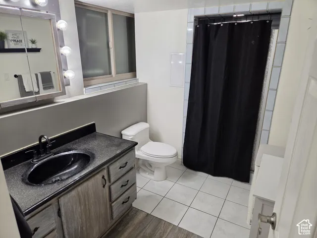 Vanity with a black basin sink, dark countertop, and wood-finish cabinetry