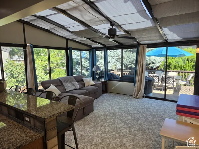 Sunroom with a sloped ceiling, overhead ceiling fan, and extensive window walls