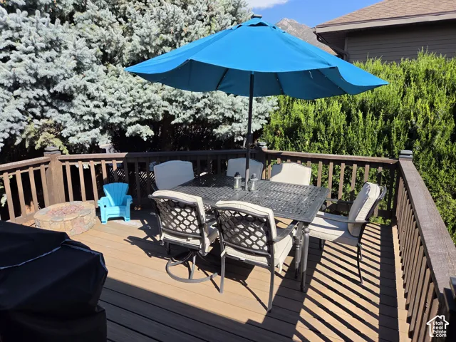 Expansive outdoor deck featuring wood-finish flooring and a stone fire pit