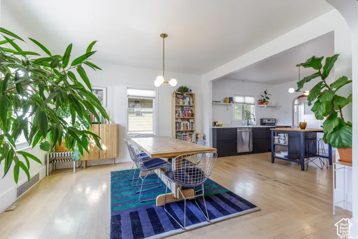 Hardwood flooring throughout, with a recessed kitchen featuring black cabinetry, stainless steel appliances, and white subway tile backsplash