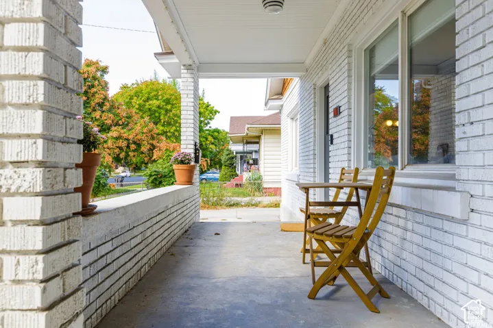 Covered porch with white painted brick walls and a concrete floor