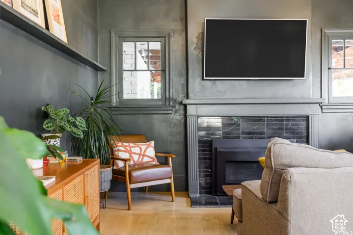 Fireplace with a dark tile surround and hearth, light wood-finish flooring, and a built-in floating shelf