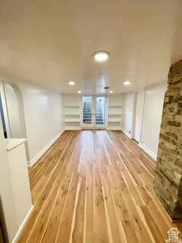 Recessed lighting illuminates the wood-finish flooring, complemented by built-in shelving and a stone-clad architectural feature
