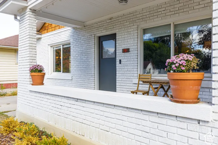 White brick exterior with a covered porch featuring a dark entry door, sliding windows, and wood soffit detailing