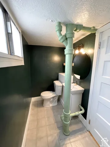 Pedestal sink with a wall-mounted round mirror and vanity lighting