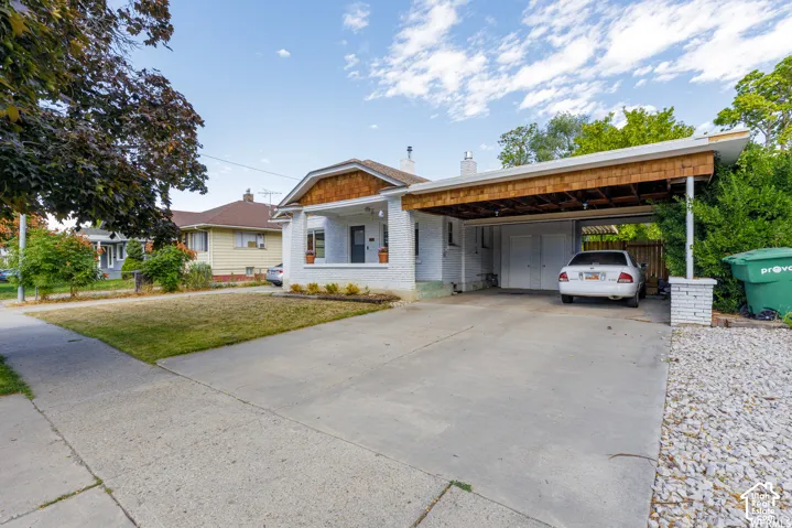 White brick exterior with a covered front porch, cedar shake accent siding, and an attached carport