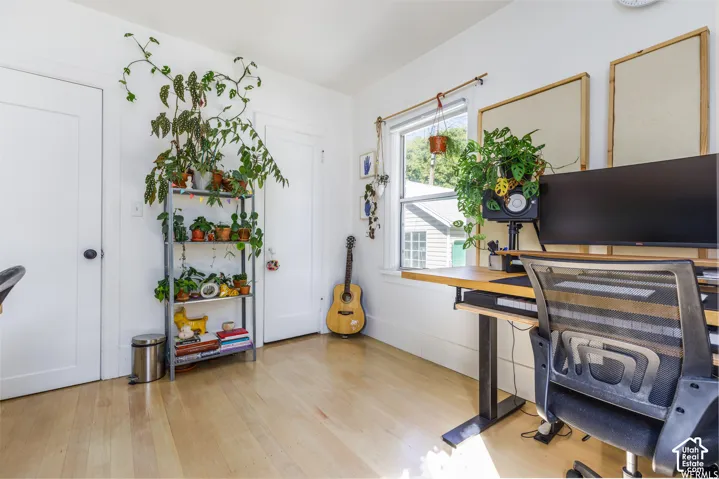 Light wood-finish flooring, white walls, and a window with natural light