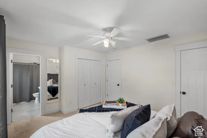 Recessed lighting, ceiling fan, white paneled doors, carpet flooring, and an adjoining bathroom with tile flooring