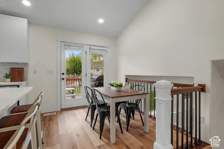 Wood-finish flooring throughout, white shaker-style cabinetry, subway tile backsplash, and white countertops